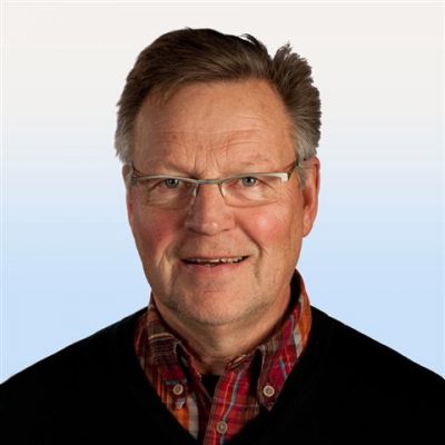 Medelålders man med glasögon, kort brunt hår, klädd i en röd rutig skjorta under en svart tröja, mot en ljusblå gradientbakgrund.
