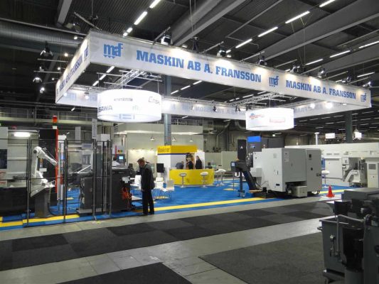 Maskin AB A. Franssons mässmonter visar upp industrimaskiner och utrustning med flera maskiner utställda och ett fåtal deltagare närvarande.