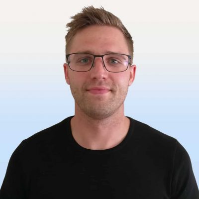 En person med kort hår och glasögon är klädd i en svart skjorta och står mot en ljus gradientbakgrund.