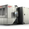 Bild på ett stort industriellt CNC-bearbetningscenter märkt "Heckert X40" från Starrag med en kontrollpanel och ett slutet arbetsområde.