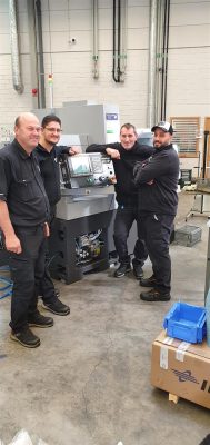 Fyra arbetare poserar med den nya Tsugami B0386E-III-maskinen i industriell miljö.